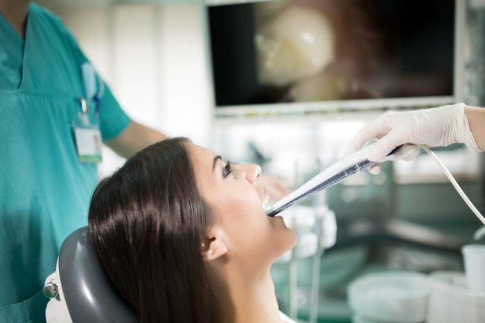 Patient undergoing dental exam with modern imaging technology in a dentist's office.