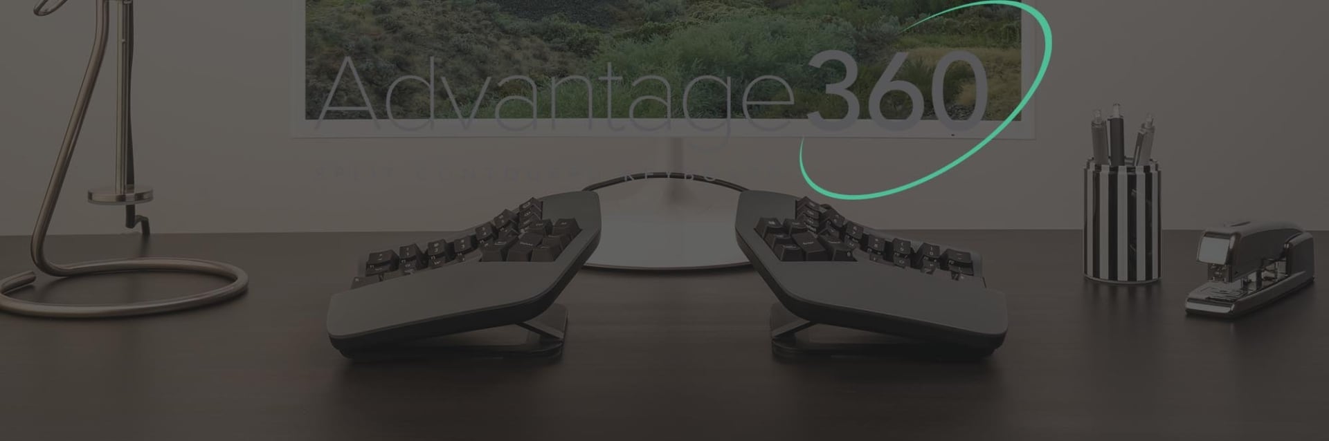 Kinesis Advantage 360 Ergonomic split keyboard setup on a modern desk with a computer monitor displaying Advantage 360.
