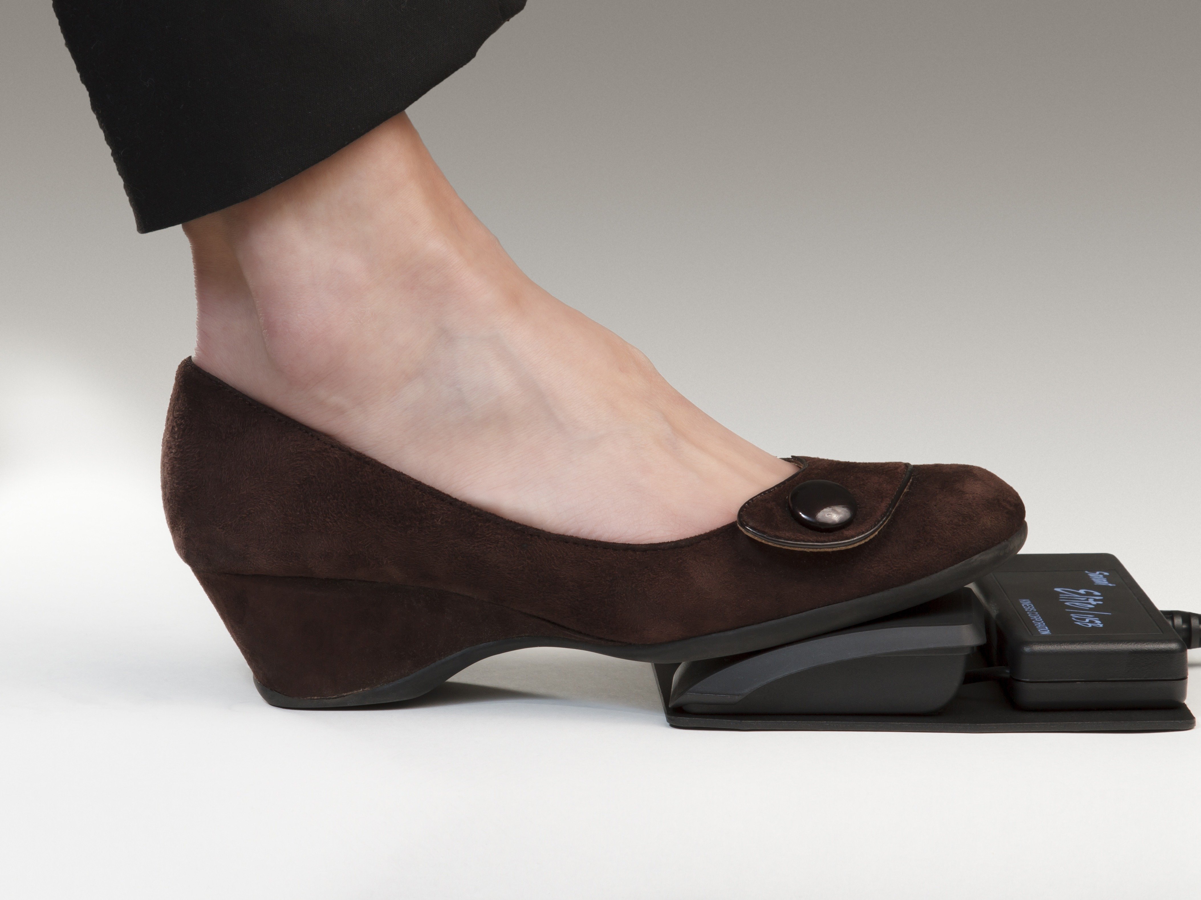 Brown wedge shoe pressing a foot pedal controller.