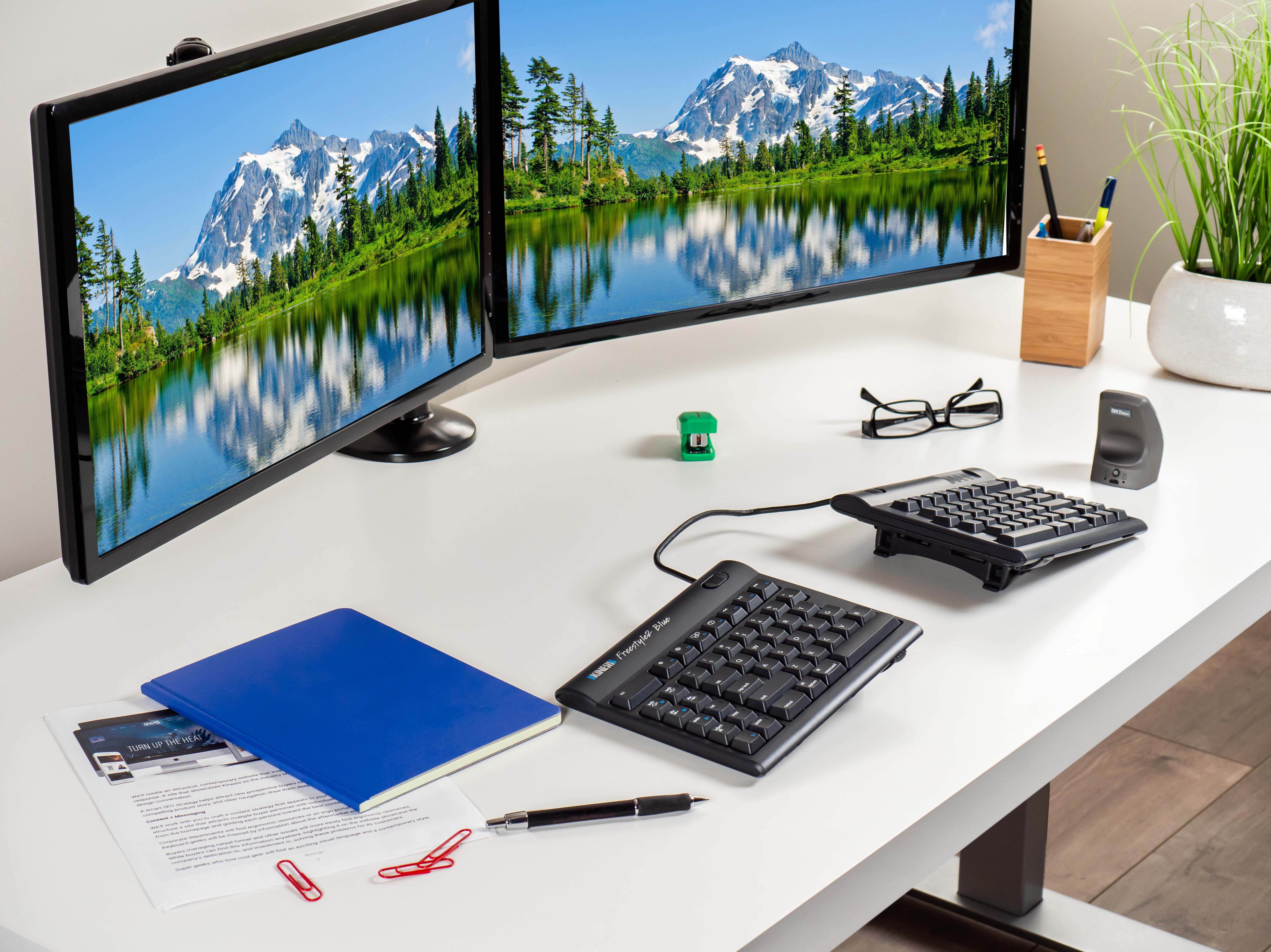 Ergonomic desk setup with dual monitors, split keyboard, and office supplies for productivity and comfort.