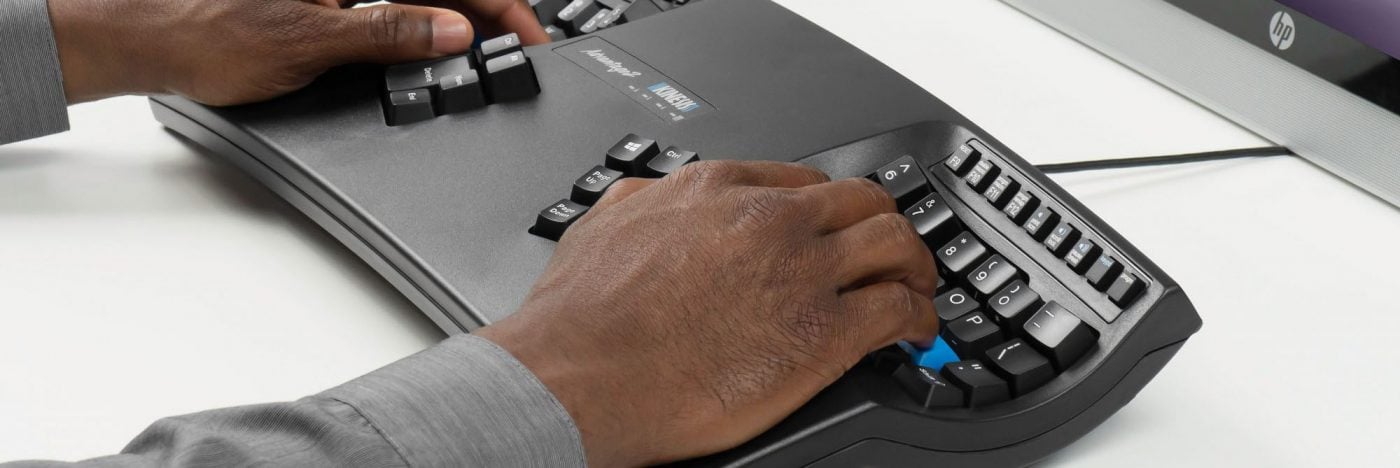 Hands typing on an ergonomic keyboard at a computer workstation.
