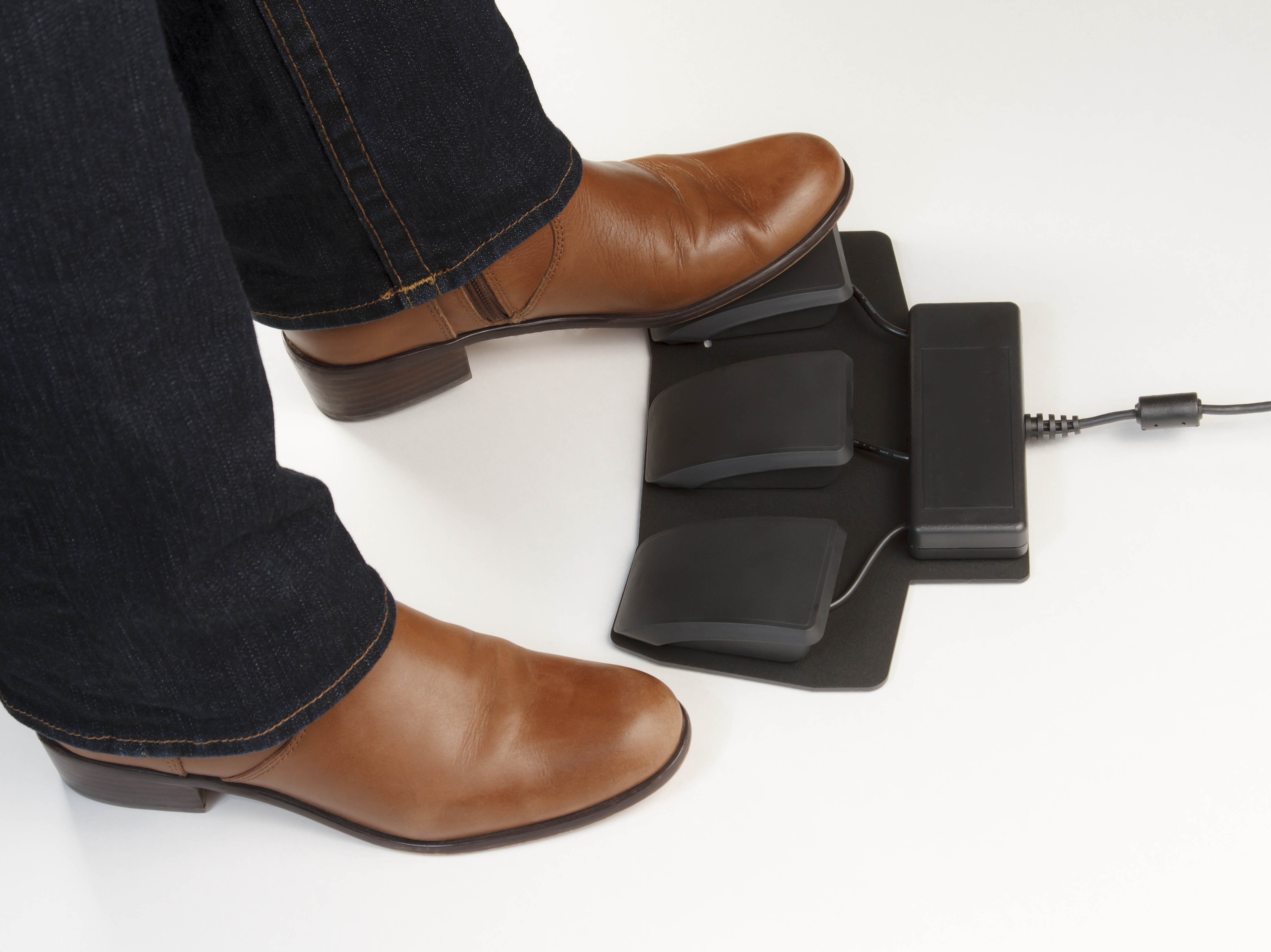 Brown boots using a USB foot pedal for computer control on a white background. Ideal for transcription or hands-free tasks.