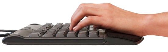 Close-up of a hand typing on a black computer keyboard, side view, emphasizing technology and digital communication.