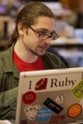 Person coding on a laptop with I love Ruby sticker in a tech workspace.