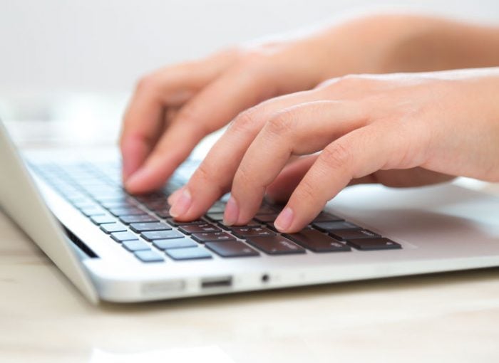Hands typing on a laptop keyboard, close-up, productivity and technology concept.