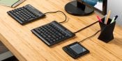 Ergonomic keyboard and keypad on a wooden desk with monitor and pen holder, ideal for efficient workspace setup.