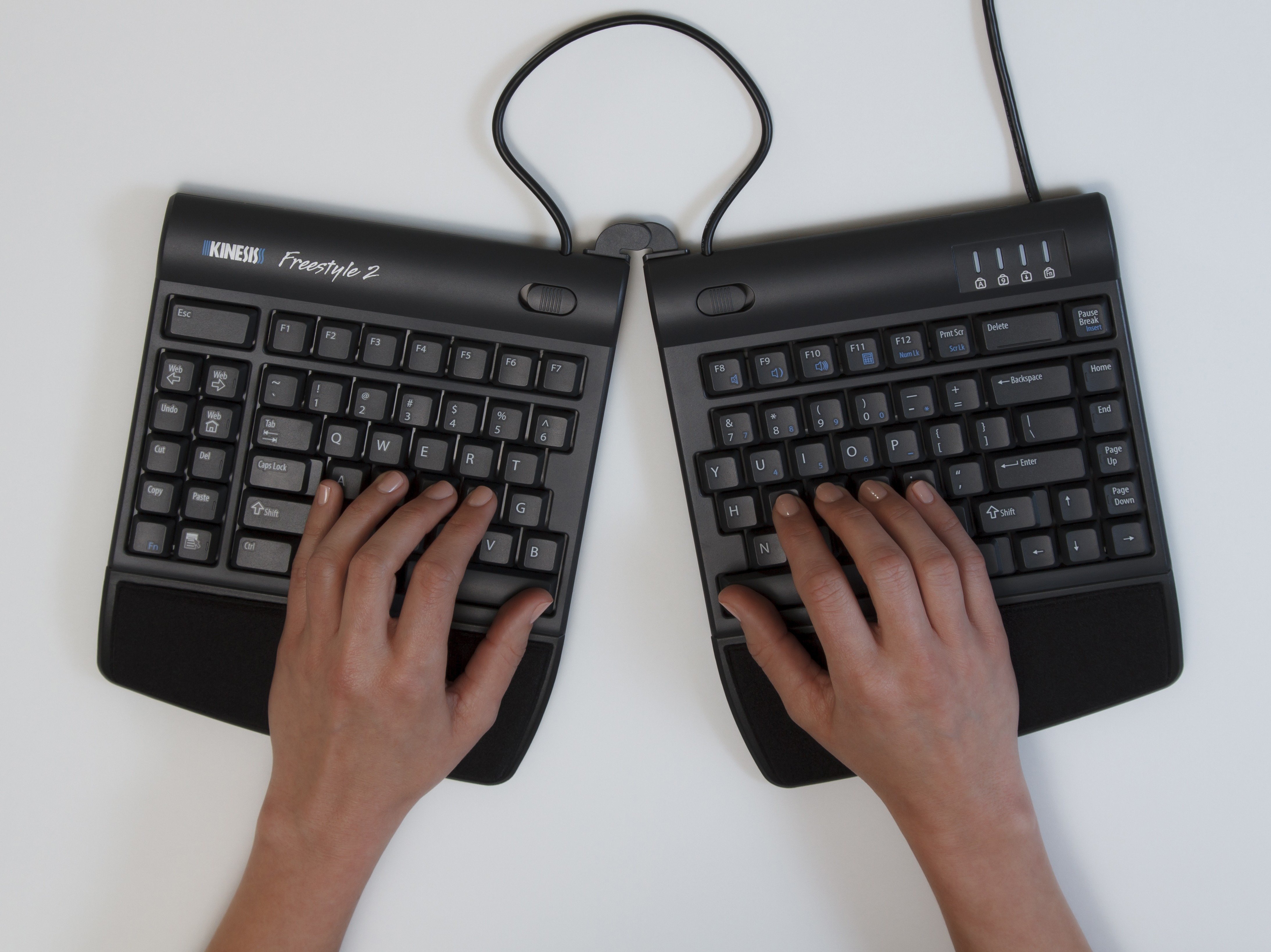Hands typing on a split ergonomic keyboard, enhancing comfort and reducing strain.