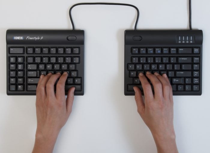Hands typing on a split ergonomic keyboard for improved comfort and productivity.
