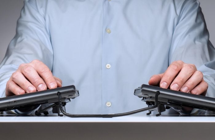 Person typing on a split ergonomic keyboard wearing a light blue shirt, emphasizing comfort and productivity.