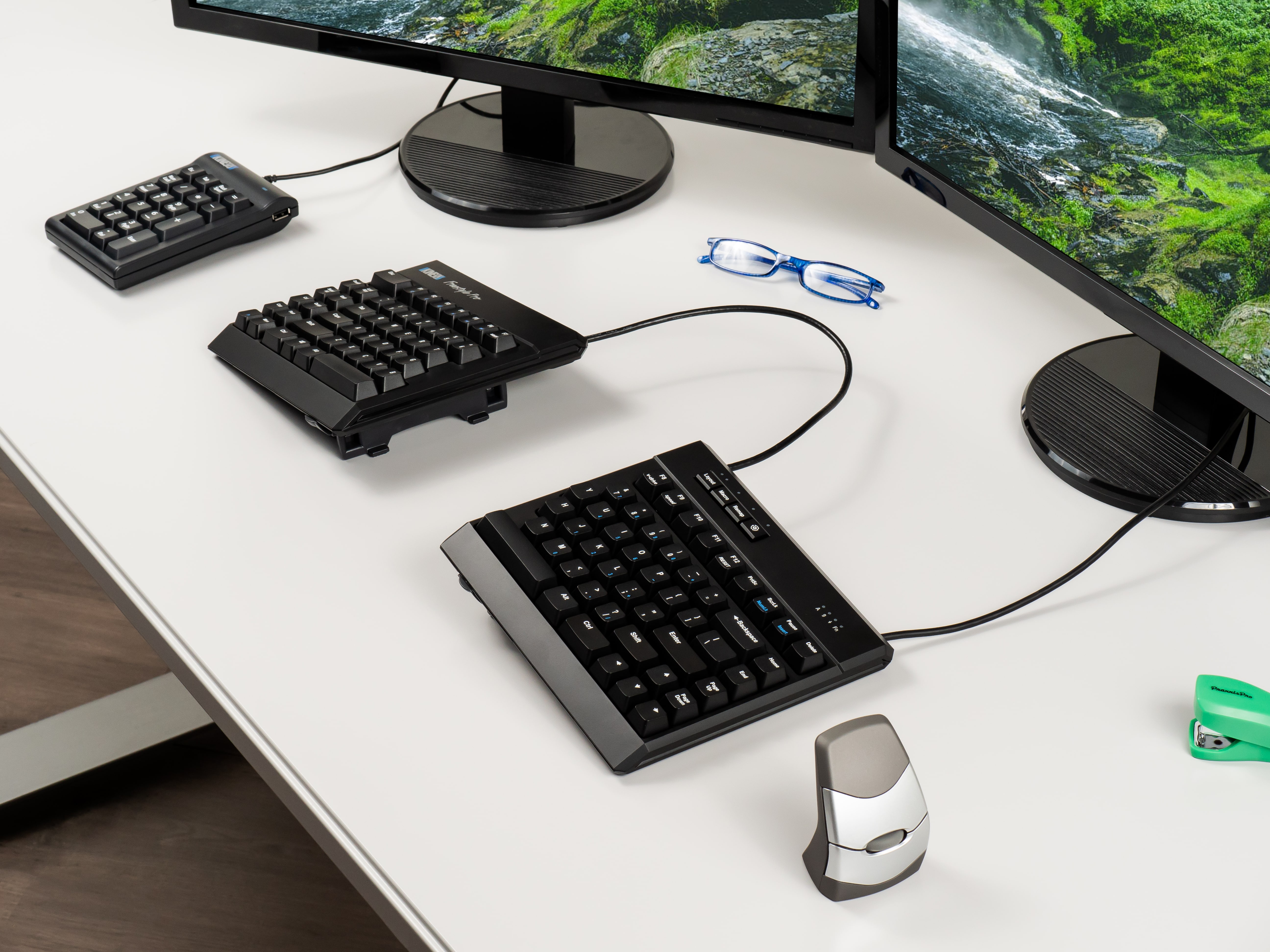 Modern dual-monitor setup with unique ergonomic keyboards and accessories on a workspace desk.