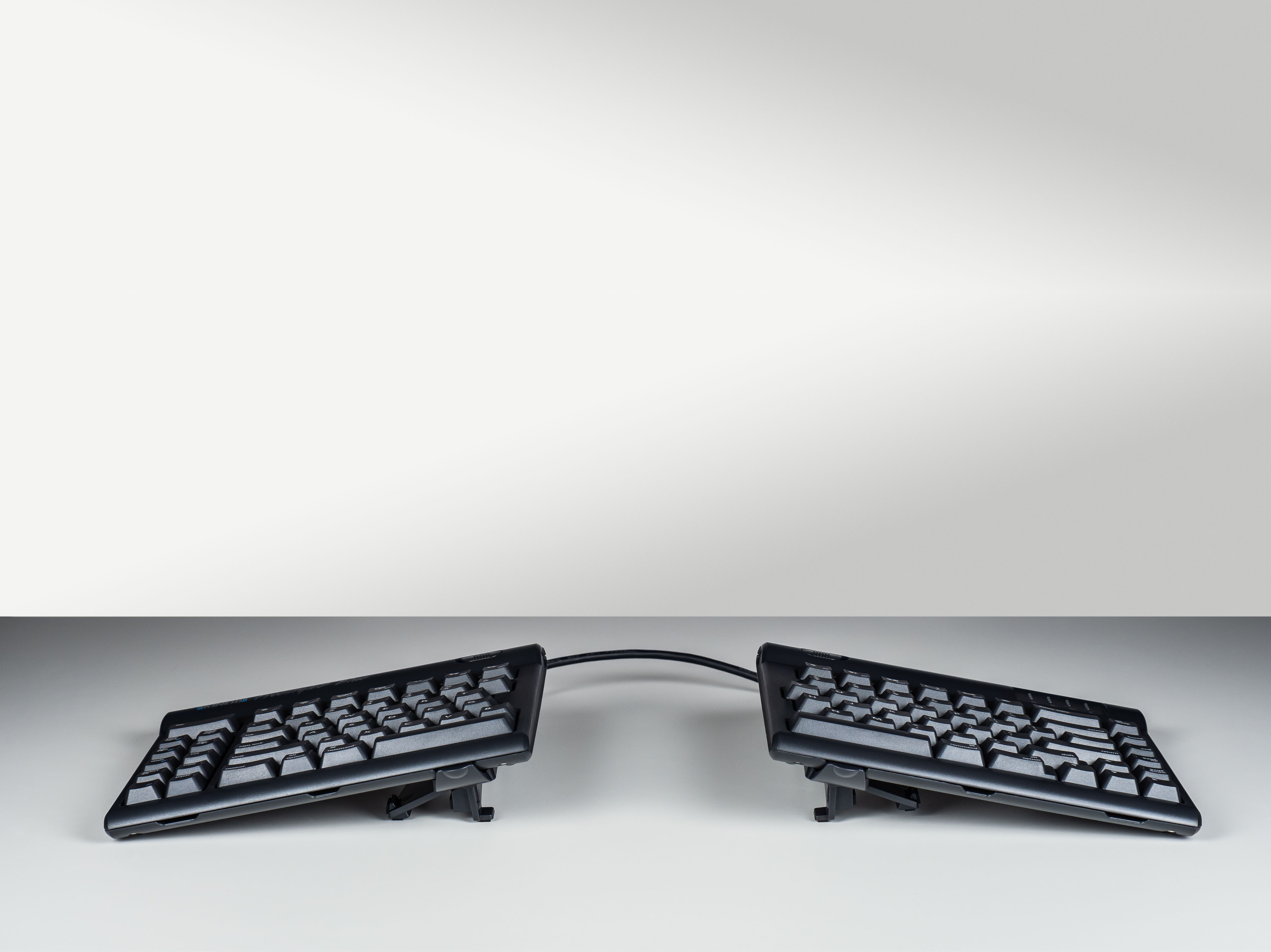 Split ergonomic keyboard with adjustable stands for improved typing comfort and posture.