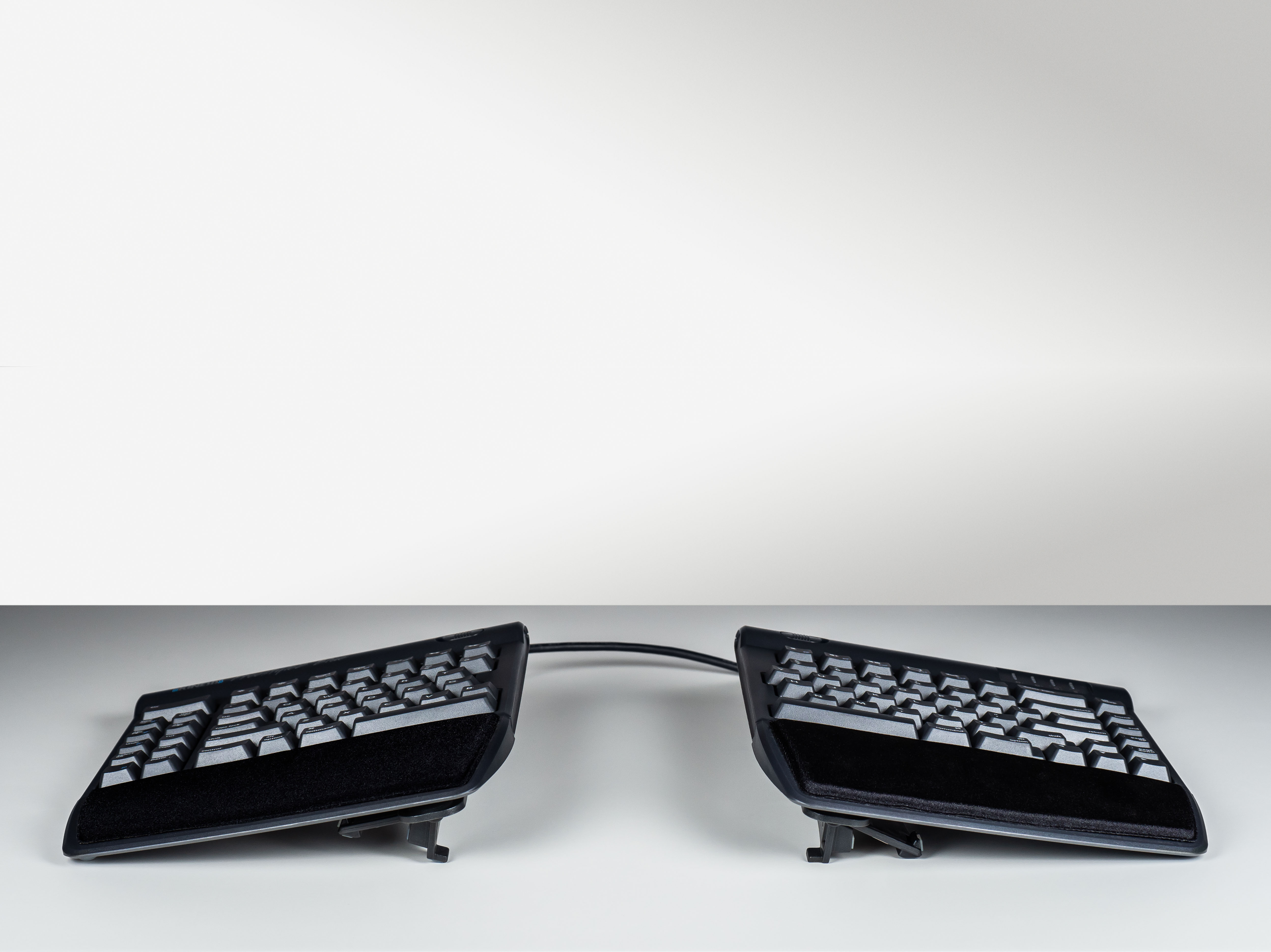 Ergonomic split keyboard with adjustable design for comfortable typing on white background.