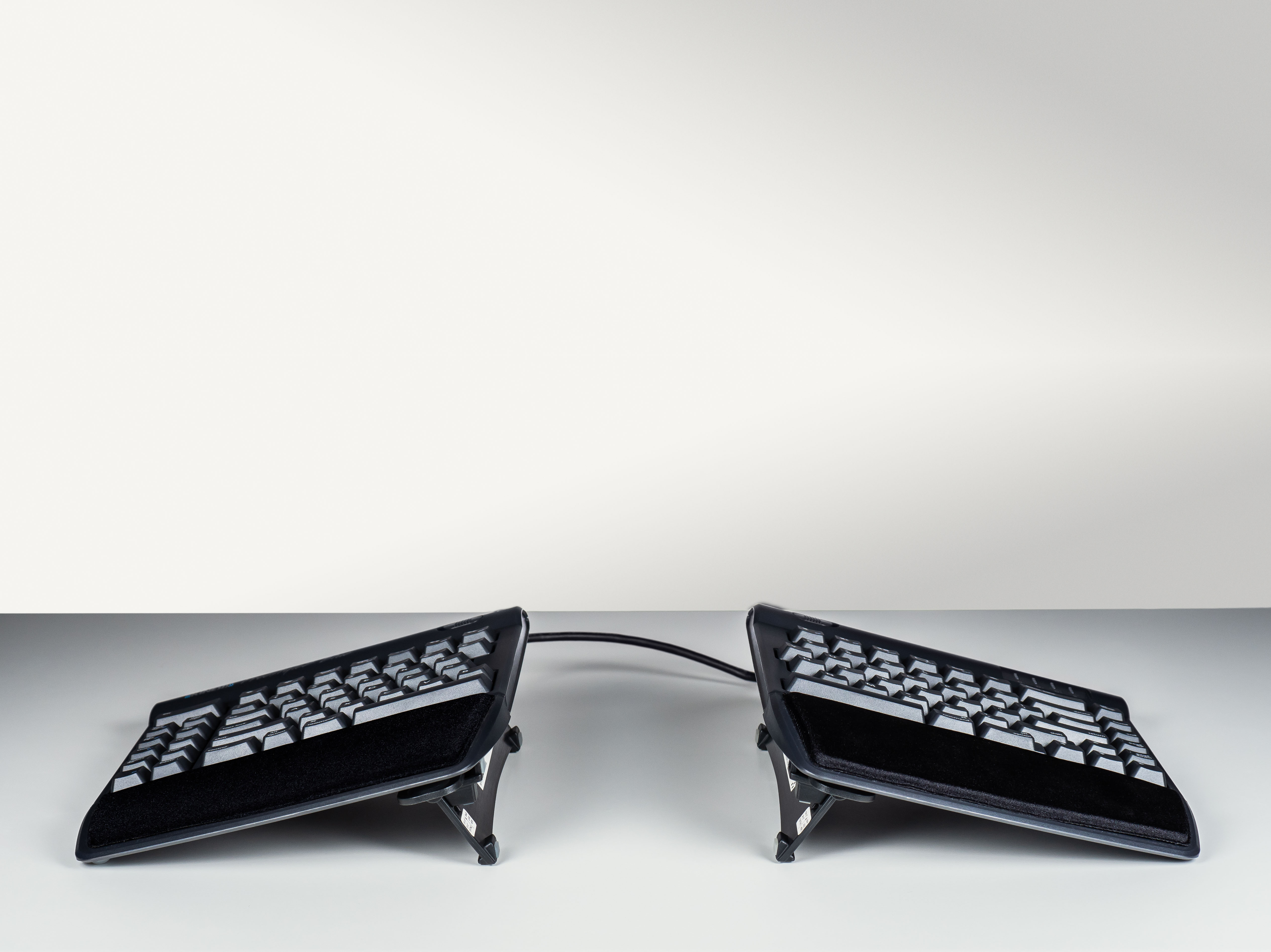 Ergonomic split keyboard with adjustable stand for comfortable typing and wrist support.