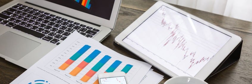 Laptop and tablet on desk displaying charts with colorful graphs, illustrating data analysis and business growth.