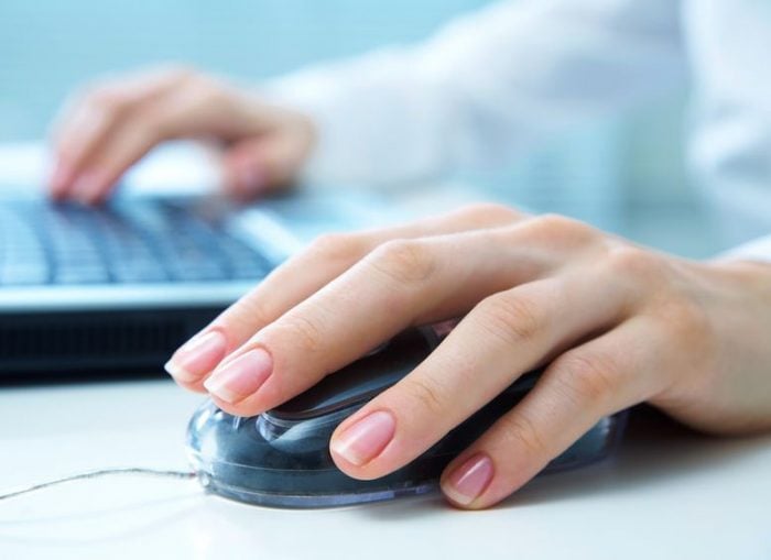 Close-up of hands using a computer mouse and keyboard, symbolizing online work or digital technology.