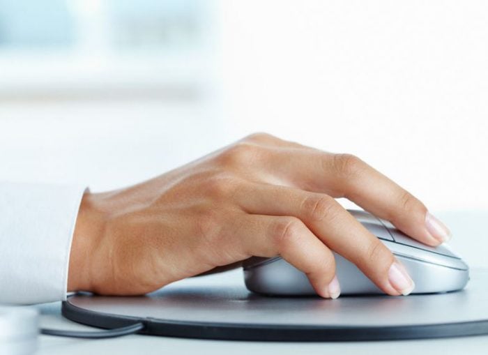 Hand on a computer mouse, representing technology and productivity in a digital workspace.