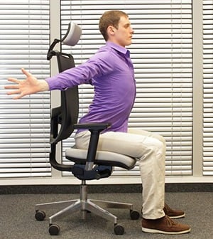 Person doing a seated back stretch in an office chair, promoting ergonomic workspace posture and wellness.