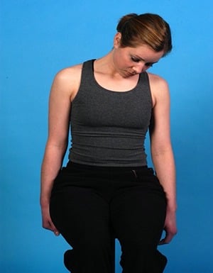 Woman performing neck stretch exercise against blue background.