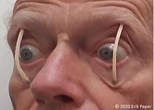 Man with wide eyes, propped open by matchsticks, showing a humorous depiction of staying awake or alert.