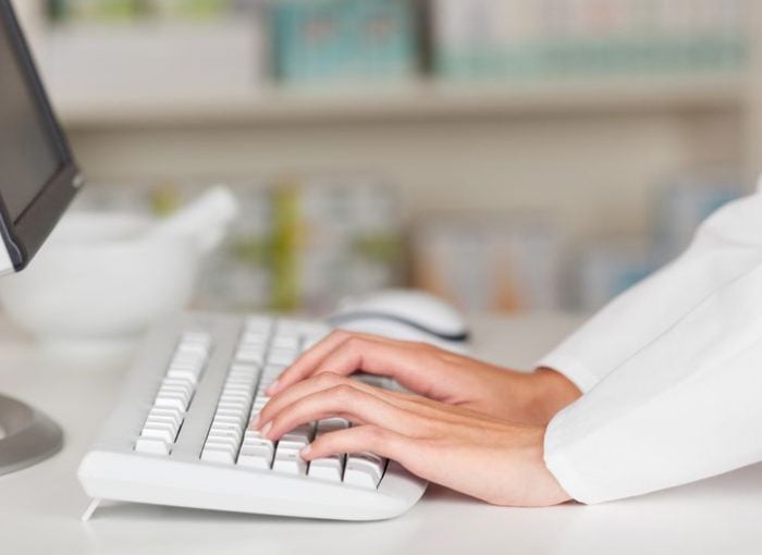 Hands typing on a white keyboard in an office setting, emphasizing productivity and modern technology.
